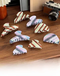 Macro detail of assorted acetate hair claws on a vintage wooden desk with books