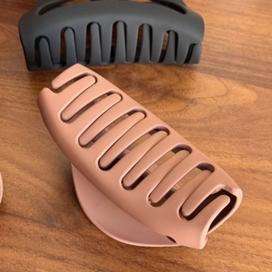 Matte black and dusty rose silicone hair claws on wood background for thick hair