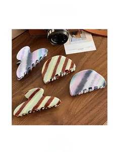 Close-up of acetic acid hair claw clips with striped and marble patterns on wood