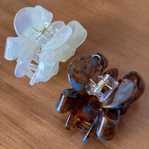 Set of two acetate bow hair claws in pearlescent white and tortoiseshell on wood