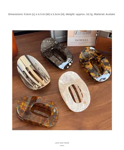 Flat acetate hair claws in tortoise and marble patterns on a vintage wooden surface