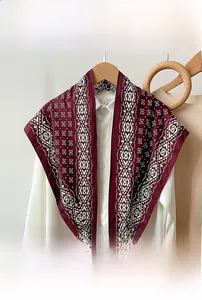 Close-up of a burgundy triangular scarf with white geometric patterns on a wooden hanger