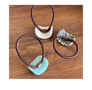 Detail of three elastic hair ties with tortoiseshell, mint green, and ivory acetate charms