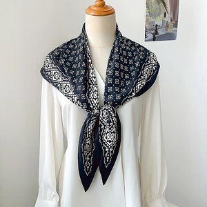 Detail of black and white geometric silk scarf draped over a classic white shirt