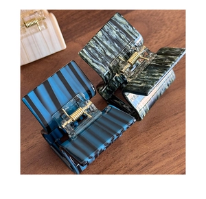Detail view of acetate claw clips showing marble textures and gold metal springs
