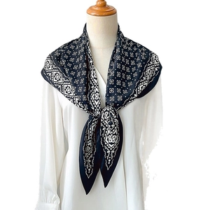Elegant black and white geometric silk scarf tied on a white shirt in a professional studio shot