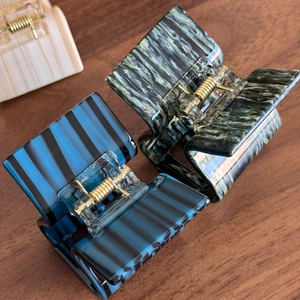 Three acetate hair claws in blue stripes, green marble and beige texture on wood