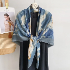 Detail shot of a blue and white tie-dye scarf with soft tassels on a minimalist background
