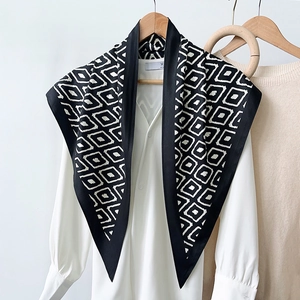 Detail of silk scarf with black white diamond pattern draped over a white shirt