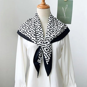 Elegant black and white geometric silk scarf displayed on a mannequin over a white shirt