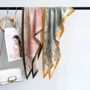 Fashionable floral silk scarves in olive green and mustard yellow hanging for display