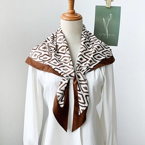 Elegant geometric diamond pattern silk scarf in coffee and beige on a white blouse