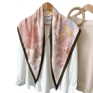 Tropical leaf print silk scarf in pink and orange tones styled on a white shirt