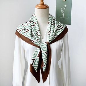 Minimalist silk scarf with green and brown diamond pattern tied on a mannequin's neck