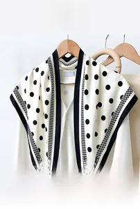 Detailed macro view of black and white polka dot silk scarf with striped edge details