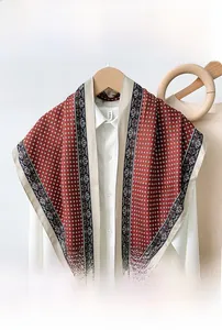 Detail of red triangle scarf with white geometric patterns and silk-like sheen
