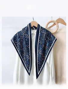 Detail of floral silk-feel scarf in navy blue draped over a white shirt on a hanger