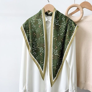 Detail of green floral silk scarf draped over a white shirt collar for elegant styling