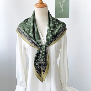 Detailed pattern of paisley and polka dots on silk scarf styled on white shirt