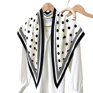 Elegant silk texture polka dot scarf with black border on a white blouse for women