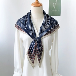Close-up of navy silk scarf with geometric patterns and vintage floral border on collar
