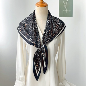 Detail showing floral silk scarf with black floral patterns and white contrast edges