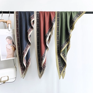 Elegant paisley triangle silk scarves in navy, rust, and green hanging on a black rack