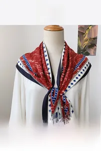 Detail of dark red printed triangle scarf with blue diamond patterns on a mannequin