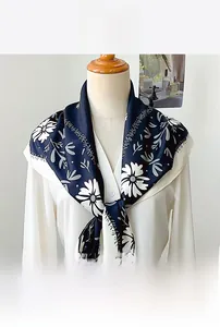 Close-up of floral print silk triangle scarf in navy blue draped on a white shirt