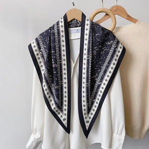 Detail of navy blue and cream printed silk scarf styled on a white shirt