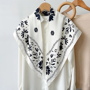 Detailed close-up of elegant black and white floral print silk scarf on white shirt