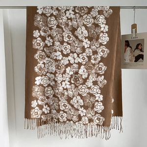 Detail of brown knitted scarf with white camellia pattern and fringe edges