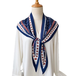 Navy blue and red geometric print silk scarf displayed on a wooden mannequin with shirt