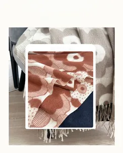 Detail of thick cashmere-like fabric with floral print and fringe trim for winter