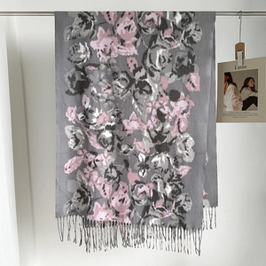 Dettaglio della stampa floreale vintage con rose rosa e nappe su calda sciarpa invernale