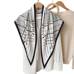 Minimalist black and white silk scarf with geometric fringe pattern on wooden hanger