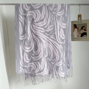 Dettaglio di sciarpa autunnale lilla con jacquard a piume bianche e bordi con frange