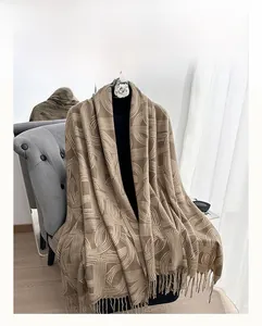 Close-up of thick winter scarf with geometric patterns and fringe detail on chair