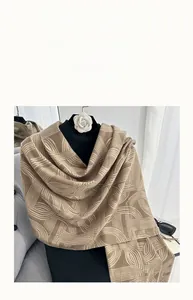 Detail of soft khaki cashmere-feel scarf with geometric patterns and fringe detail