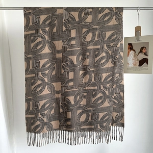 Detail of khaki fringed scarf with grey interlocking geometric pattern and soft texture