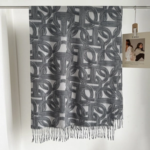 Detail view of winter cashmere-like scarf with grey geometric pattern and tassel fringe