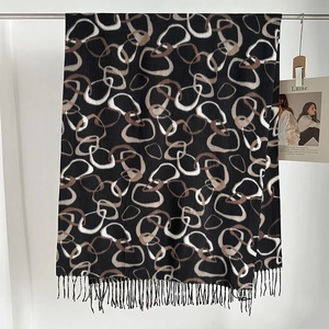 Detail of soft knit scarf with brown geometric ring patterns and fringe tassels