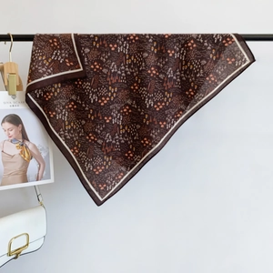 Vue détaillée d'un foulard en soie marron foncé à fleurs drapé sur une barre