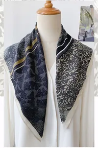 Detailed macro view of herringbone print silk scarf in black, cream, and golden brown tones