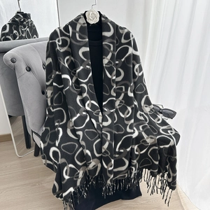 Detailed view of thick knit scarf fabric with geometric rings and fringe edges
