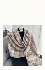 Détail d'une écharpe chaude style cachemire avec motif rose camélia et texture à carreaux