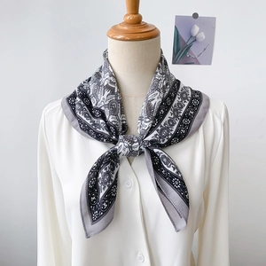 Fashionable floral square silk scarf tied in a bow on a white collared shirt