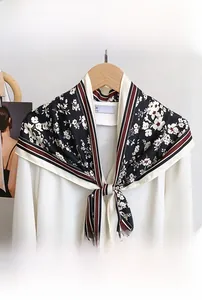 Detail of floral triangular scarf tied on white shirt with stripe edge design
