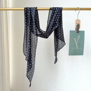 Chic black and white polka dot silk cotton scarf hanging on a minimalist golden rack