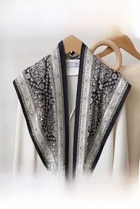 Détail d'un foulard triangle noir et blanc à motif paisley sur un pull beige